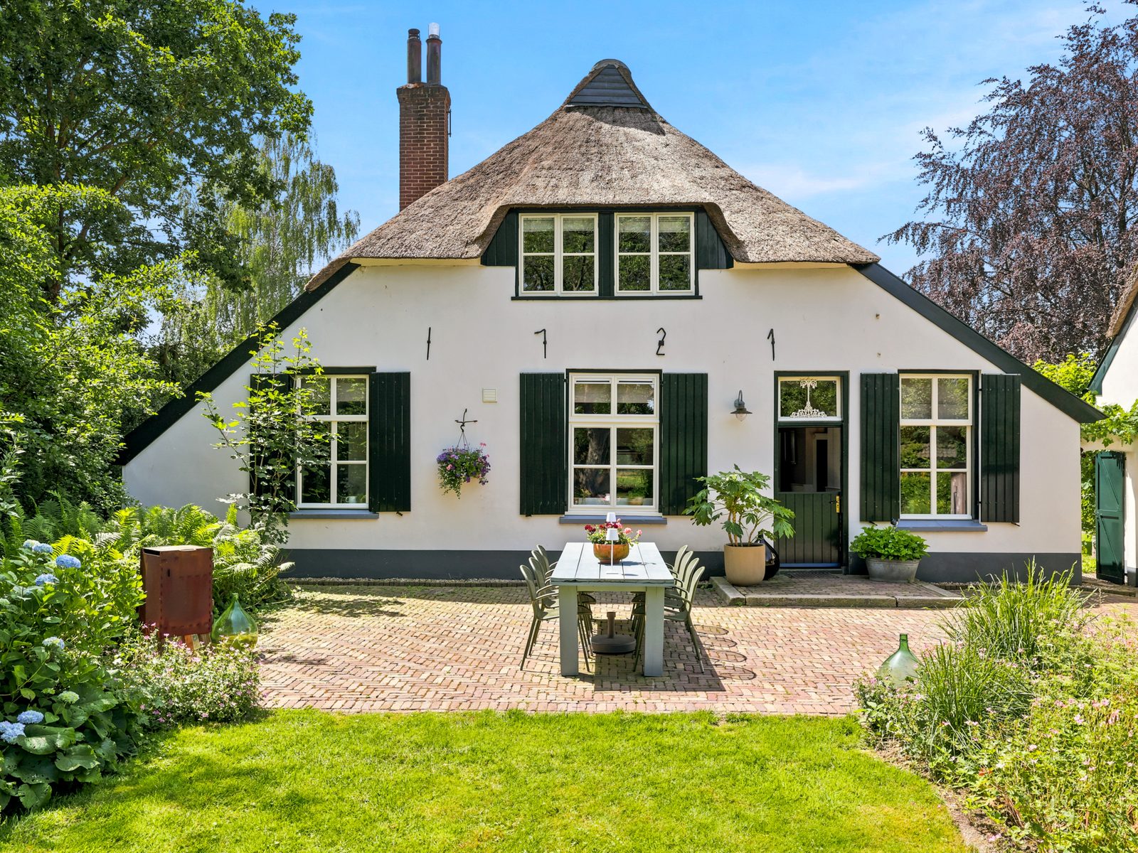Witte boerderij met rieten dak en terras